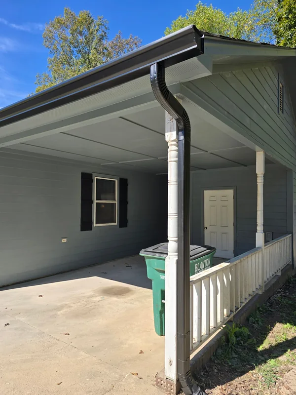 Black gutter and downspout on a gray covered porch