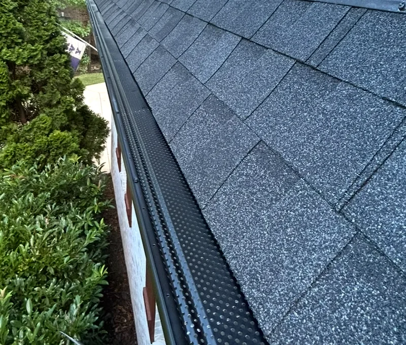 Black perforated gutter covers along a gray shingle roof
